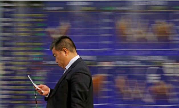 A man walks past an electronic stock quotation board outside a brokerage in Tokyo, Japan, February 9, 2018. REUTERS/Toru Hanai