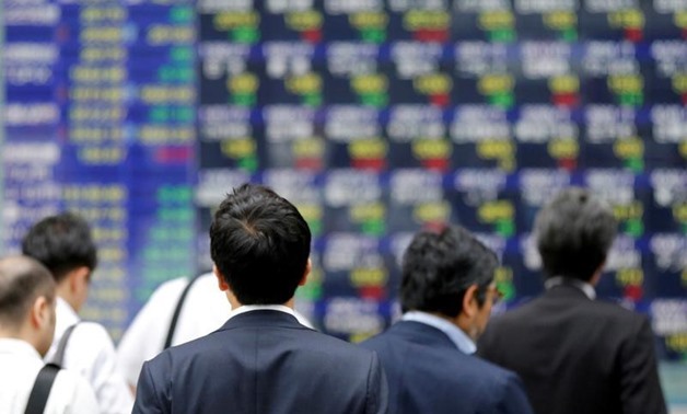 FILE PHOTO: People walk past an electronic stock quotation board outside a brokerage in Tokyo, Japan, September 22, 2017. REUTERS/Toru Hana