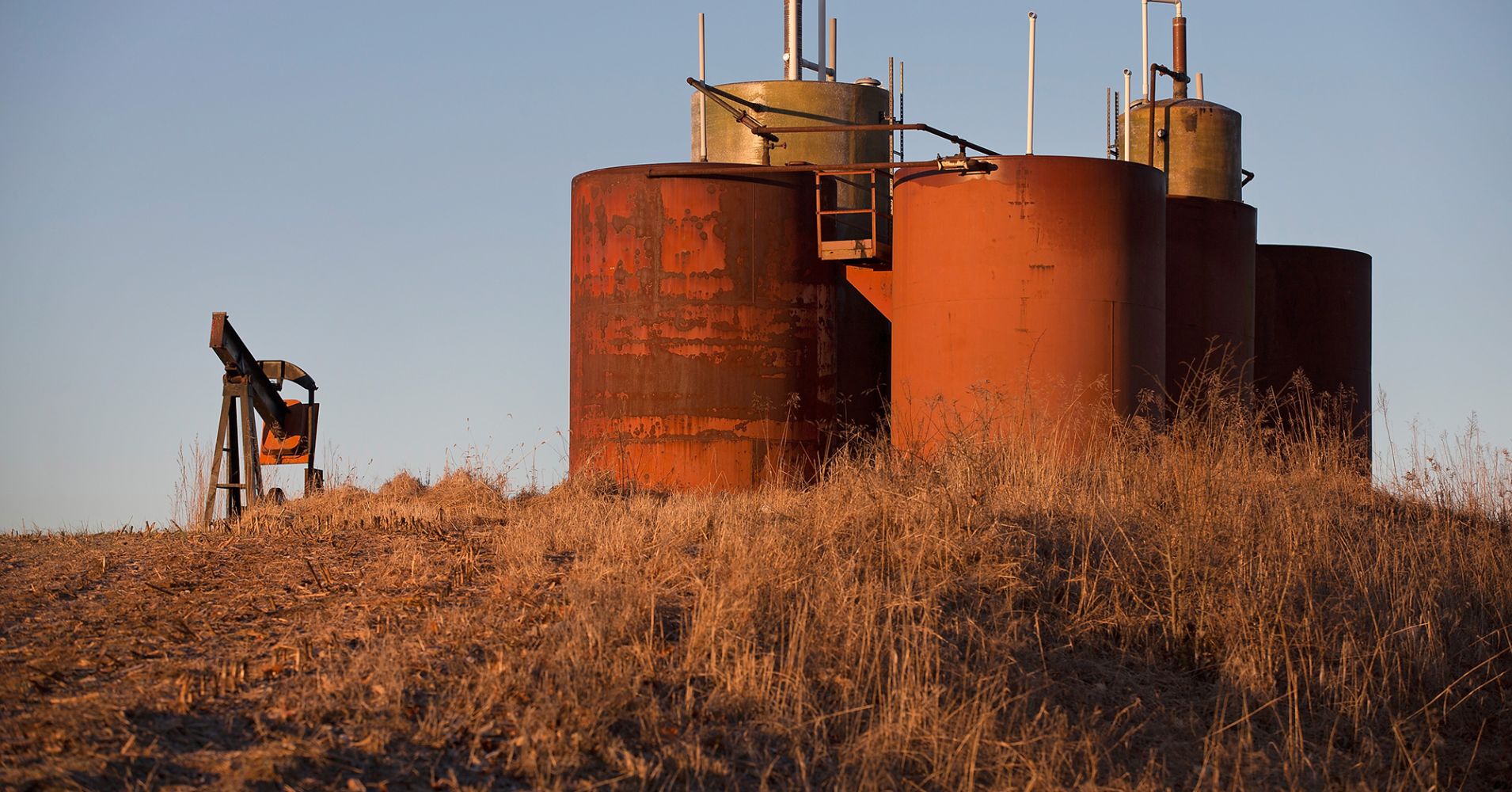 An idled pump jack, once used to extract crude oil from the ground, and a tank battery, used to temporarily store freshly-pumped crude, rust in a farmer's field near Ridgway, Ill., Jan. 21, 2015.