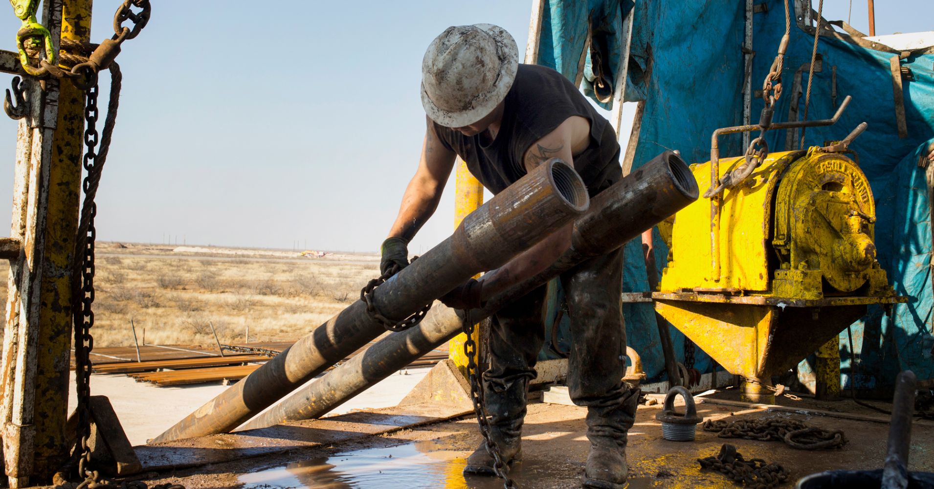 A worker prepares to lift drills by pulley to the main floor of a drilling rig in the Permian basin.