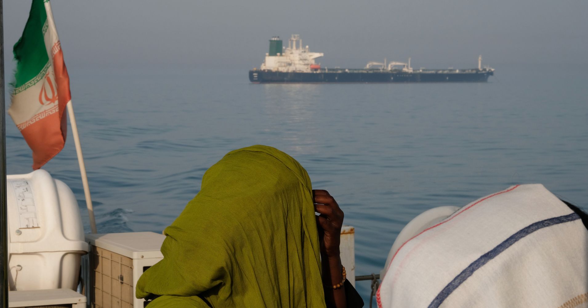 Foreign tourists in veils seen on a passenger boat with the Iranian flag amass in the waters of the Strait of Hormuz on May 2, 2017 near Hormuz Island, Iran. An oil tanker is seen on the move in the background. 