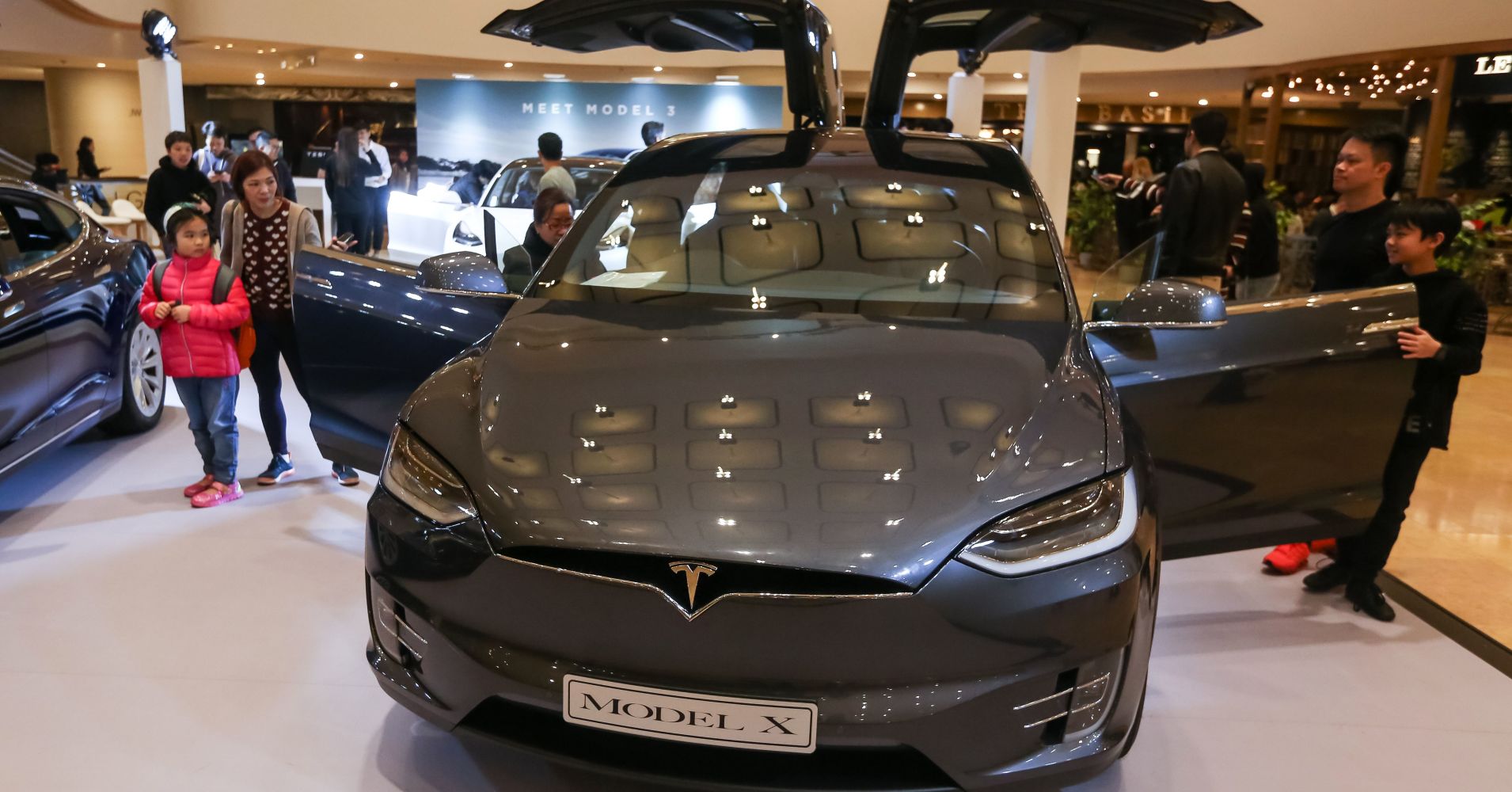 People look at a Tesla Model X displayed at a shopping mall in Hong Kong on March 10, 2019