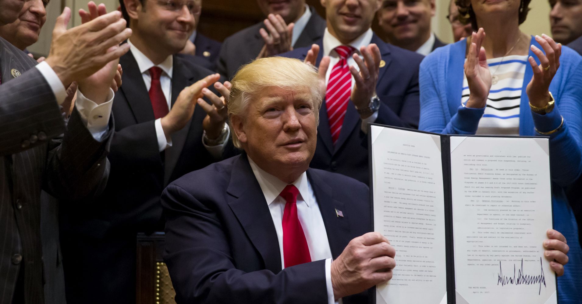 U.S. President Donald Trump holds up a signed executive order on implementing an America-first offshore energy strategy in the Roosevelt Room of the White House in Washington, D.C., U.S., on Friday, April 28, 2017.