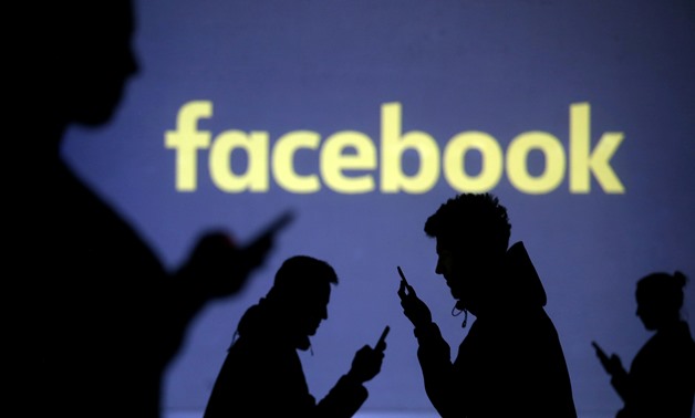 FILE PHOTO: Silhouettes of mobile users are seen next to a screen projection of Facebook logo in this picture illustration taken March 28, 2018. REUTERS/Dado Ruvic/Illustration